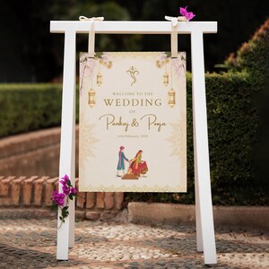 May include: A white wooden wedding sign with the text "WELCOME TO THE WEDDING of Pankaj & Pooja" in elegant script. The sign features floral and lantern illustrations, and a date. A couple in traditional attire is depicted at the bottom.