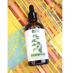 May include: A brown glass bottle with a black dropper, labeled "Lucky Forest." The label features a green illustration of a plant and the word "Ashwagandha." The bottle contains 4 fl oz of double extraction tincture.