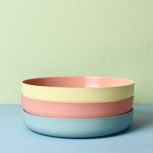 Może przedstawiać: Stos czterech ceramicznych misek w pastelowych kolorach. Miski są w odcieniach jasnoniebieskiego, r&oacute;żowego i ż&oacute;łtego. Miski są ułożone jedna na drugiej, z niebieską miską na dole i ż&oacute;łtą miską pośrodku.