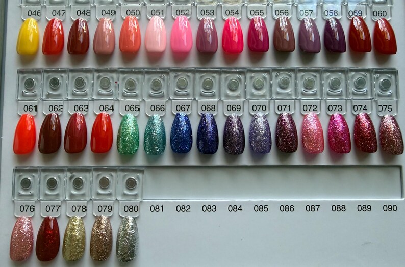 Pu&ograve; includere: Una cartella colori per smalti con file di punte per unghie ovali in varie finiture, tra cui texture crema solide, neon e glitterate. Ogni punta &egrave; numerata da 046 a 090, mostrando un ampio spettro di colori.