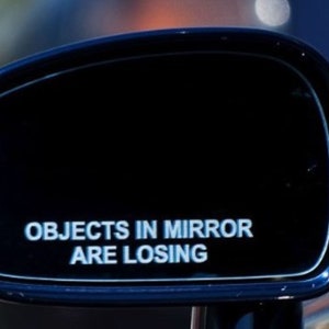 May include: A black car side mirror with the text "Objects in mirror are losing" printed in white.
