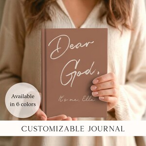 May include: A terracotta-colored hardcover journal featuring the white text "Dear God." in a large script font, followed by the smaller white text "It's me, Ella." A circular white graphic on the left side contains the text "Available in 6 colors."