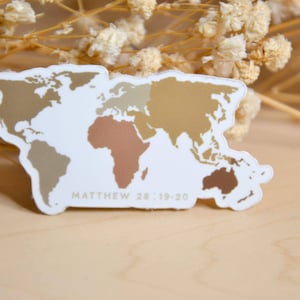 May include: A die-cut sticker featuring a world map with continents colored in various shades of gold, tan, and brown against a white background. The text MATTHEW 28:19-20 is printed in small white capital letters at the bottom of the map design.