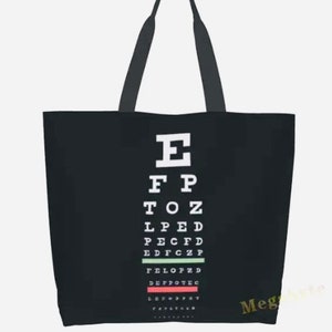 May include: Black canvas tote bag with a white eye chart design. The chart features the letters E, FP, TOZ, LPED, PECFD, EDFCZP, FELOPZD, DEFFOTEC, LEFPOPYT, and YFPOTLFC.