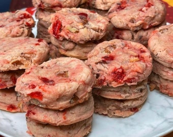 May include: A close-up of a plate of pink and white cookies with red and white sprinkles. The cookies are stacked on top of each other and are arranged in a circle.