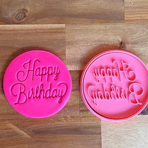 May include: Two pink silicone cookie cutters with the words "Happy Birthday" in a cursive font.