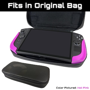 May include: A black carrying case with a hot pink game console inside. The console has a black screen and black controls. The case is open, and a smaller black case is below it. Text at the top reads "Fits in Original Bag".