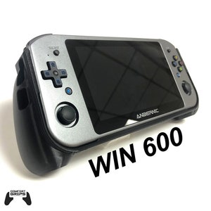 Puede incluir: Una consola de juegos portátil plateada con detalles negros y una pantalla que muestra el texto "ANBERNIC WIN 600".