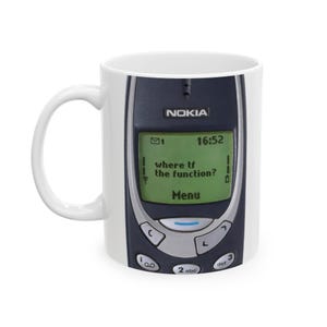 Może przedstawiać: Biały kubek ceramiczny z nadrukowanym czarno-szarym telefonem komórkowym Nokia. Ekran telefonu wyświetla tekst "where tf the function?" i "Menu".
