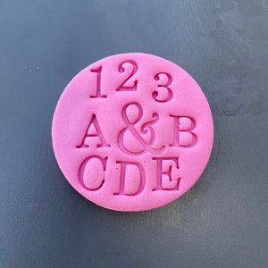 May include: Pink silicone stamp with the numbers 123 and the letters A&B CDE.