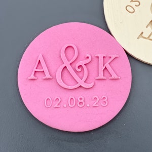 May include: Pink round rubber stamp with the letters A & K and the date 02.08.23.