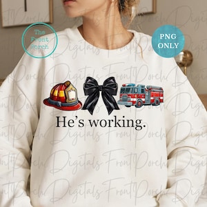 May include: A white sweatshirt with a red fire helmet, a black bow, and a red fire truck with the text "He's working." printed on it.
