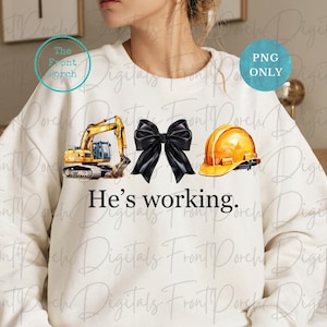 Może przedstawiać: Biała bluza z żółtą koparką, czarną kokardką i żółtym kaskiem. Pod obrazkami znajduje się napis "He's working."