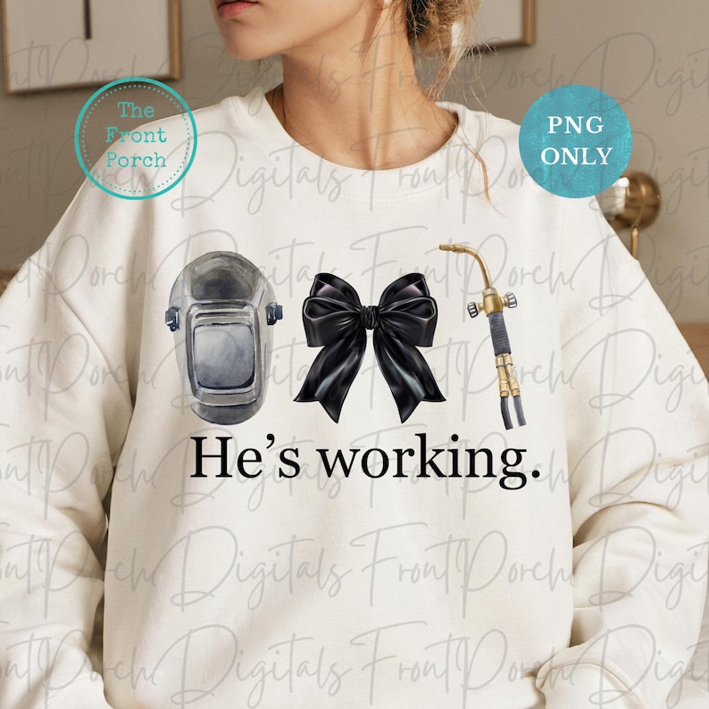 May include: A white sweatshirt with a black bow, a welding mask, and a welding torch. The text "He's working." is printed on the sweatshirt.