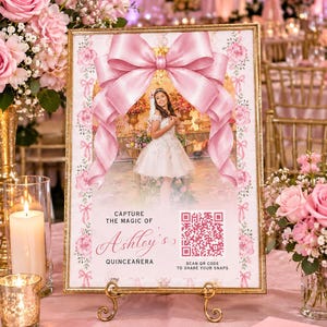 May include: A rectangular sign in a gold frame featuring a large pink bow graphic, a photo of a person in a white dress, and text that reads Capture the magic of Ashley's Quinceañera, along with a QR code to scan to share your snaps.