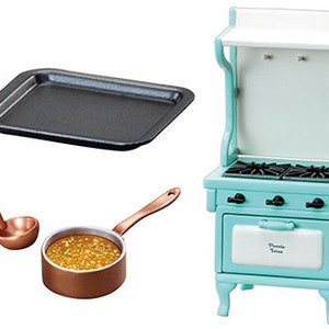 May include: A miniature kitchen set with a blue and white stove, a copper pot with a ladle, and a black baking sheet.