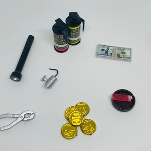 May include: A set of toy props including two yellow and red smoke grenades, a flashlight, a pair of pliers, a small silver object, a stack of toy money, a toy lighter in a black ashtray, and a pile of gold coins.