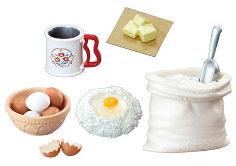 May include: A set of miniature baking supplies, including a bag of flour, a scoop, a bowl of eggs, a cup of milk, a stick of butter, and a bowl of batter with an egg yolk in the center.