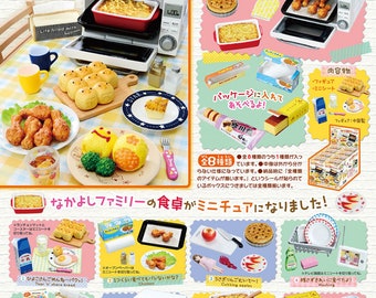 Op de afbeelding: Een set van acht miniatuurvoedingsmiddelen, waaronder een ovenschaal, een brood, een bord gebakken kip en een bord fruit. De set maakt deel uit van een grotere collectie genaamd "Mama's Diner", een miniatuurvoedselcollectie om mee te spelen of te exposeren.