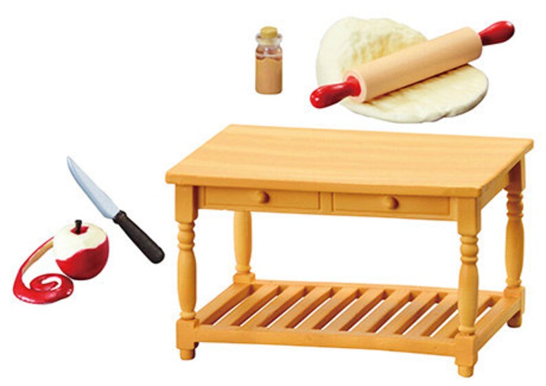 May include: A miniature wooden kitchen table with two drawers and a bottom shelf. There is a rolling pin and dough, a knife and a peeled apple, and a small glass jar with a cork lid.