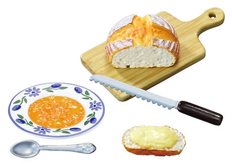 May include: A miniature kitchen set with a loaf of bread on a wooden cutting board, a serrated knife, a plate with orange jam, a spoon, and a slice of bread with butter.