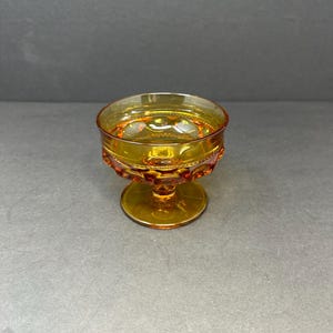May include: A small amber glass goblet with a textured design and a short stem. The goblet is ideal for serving small portions of dessert or drinks.