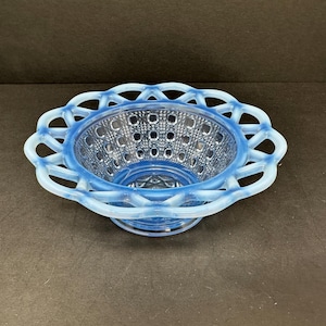 May include: A blue and white milk glass bowl with a scalloped edge and a raised pattern. The bowl is made of opaque glass and has a delicate, feminine look.