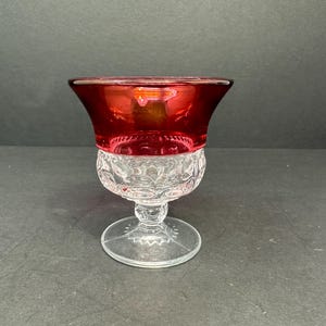 May include: A clear glass goblet with a cut glass design and a red glass top.
