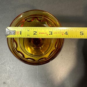 May include: Amber glass dessert dish with a scalloped edge and a decorative pattern. The dish is 7.6 cm in diameter.