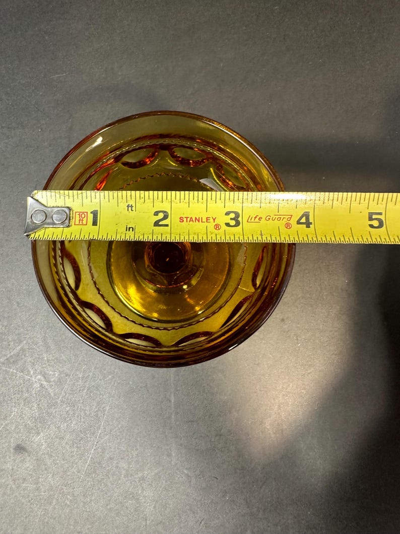 May include: Amber glass dessert dish with a scalloped edge and a decorative pattern. The dish is 7.6 cm in diameter.