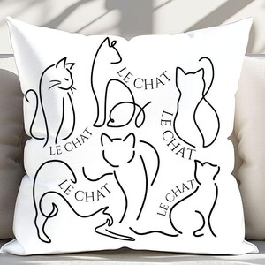 May include: White throw pillow with black line drawings of cats and the text "Le Chat" repeated throughout the design.
