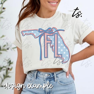 May include: Cream-colored t-shirt featuring a Florida outline design with red, white, and blue accents. The design includes the letters "FL" in a plaid pattern and a star-spangled outline. The words "design example" are at the bottom.