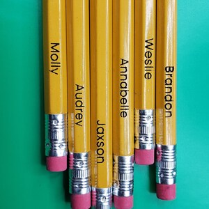 May include: Six yellow pencils with names written on them: Molly, Audrey, Jaxson, Annabelle, Weslie, and Brandon. The pencils are arranged in a row with their erasers facing the viewer.