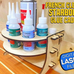 May include: A wooden French cleat Starbond glue caddy with four bottles of glue and a can of spray adhesive. The caddy is designed to hold the bottles upright and has a shelf for the can. The caddy is made of wood and has a natural finish. The text "DIGITAL LASER FILES" is printed on a blue circle in the lower right corner of the image.