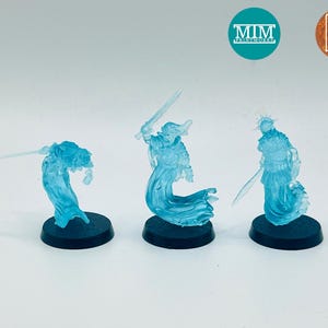 Könnte beinhalten: Drei durchscheinende blaue Miniaturfiguren von Geisterkriegern, die jeweils ein Schwert halten. Sie stehen auf schwarzen kreisförmigen Sockeln. Die Figuren sind detailliert mit fließenden Gewändern und Rüstungen. Der Hintergrund ist schlicht weiß.