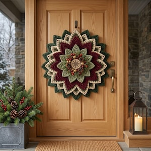 May include: A circular crochet wreath featuring layered, pointed petals in shades of dark red, cream, and forest green. The center is decorated with small pinecones, red berries, and a round wooden ornament engraved with a snowflake design.