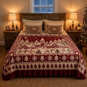 May include: A deep red and cream knit blanket featuring a winter village scene with houses, a church, pine trees, and a snowman. The border displays repeating snowflake and tree patterns, and the blanket is finished with a ruffled bottom edge.