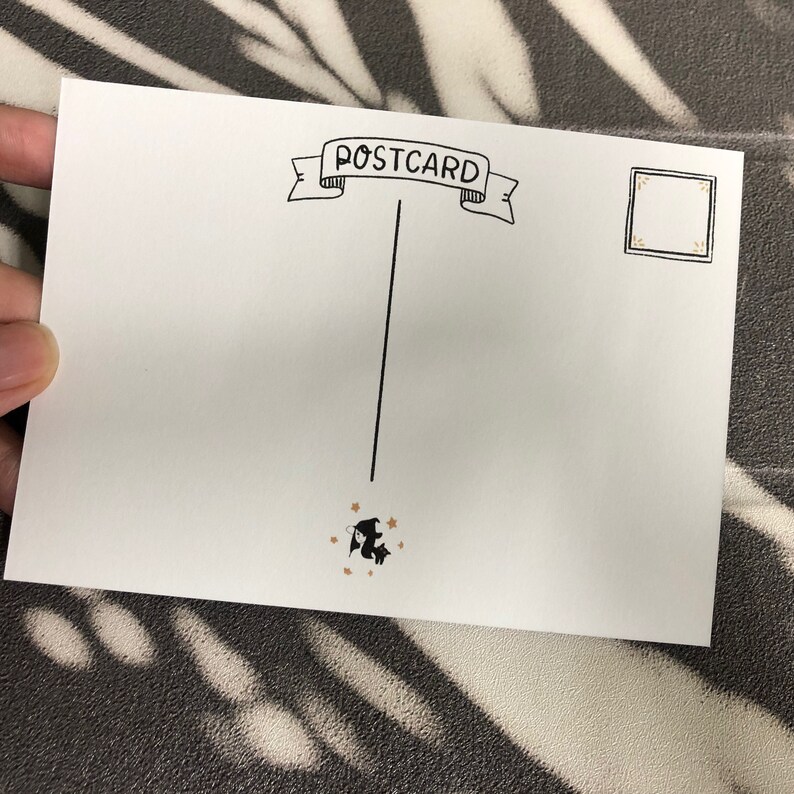 May include: A blank white postcard with the word "POSTCARD" written in black cursive on a banner at the top. A black and white illustration of a bat flying with gold stars is at the bottom. There is a blank space for a stamp in the upper right corner.