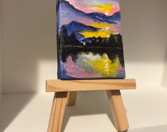 miniature painting of a mountain and lake sunset with easel