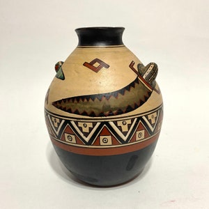 May include: A hand-painted ceramic vase with a black, brown, white, and green geometric design. The vase has a rounded body and a small opening at the top.