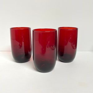 Könnte beinhalten: Drei rote Glasbecher mit einem Farbverlauf von dunklem Rot am Boden zu hellem Rot oben.