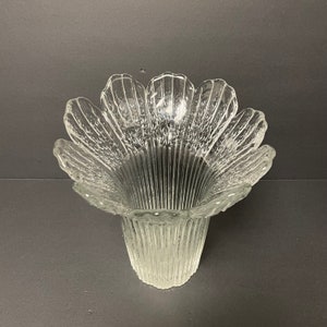 May include: A clear glass vase with a textured, flower-shaped opening and a ribbed, cylindrical base.