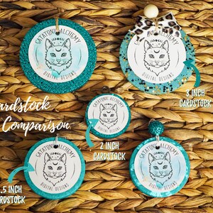 May include: A size comparison of four round teal and gold glitter cardstock circles with a black and white cat illustration and the text "Catatonic Alchemy Digital Designs". The circles are 2.5 inches, 2 inches, and 3 inches in diameter.