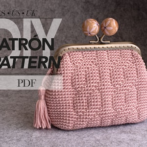 Könnte beinhalten: Eine handgefertigte rosa Häkeltasche mit Metallverschluss und dekorativen Holzperlen. Die Tasche hat eine passende Quaste und den Text "DIY PATRÓN PATTERN PDF". Die Tasche liegt auf grauem Hintergrund.