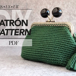 Peut inclure: Une bourse à main en crochet de couleur verte avec une fermeture à fermoir argentée et deux embellissements ronds noirs. La bourse a un pompon et une étiquette qui dit "Made with Love". L'image comprend également le texte "DIY PATRÓN PATTERN PDF".