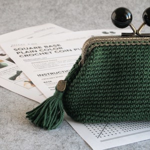 May include: A green crocheted coin purse with a metal clasp and two black round knobs. The purse has a green tassel attached to it and a tag that says "Made with Love".