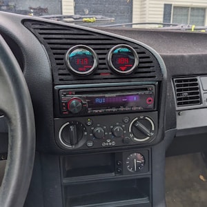 May include: The interior of a car with a black dashboard, a stereo system, and two round gauges with red digital displays. The gauges read "8.8" and "10.8".