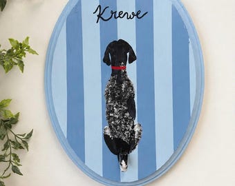 May include: An oval wooden wall plaque featuring a painted black and white speckled dog viewed from behind, wearing a red collar. The background consists of vertical light and medium blue stripes, with the word Krewe written in black script.