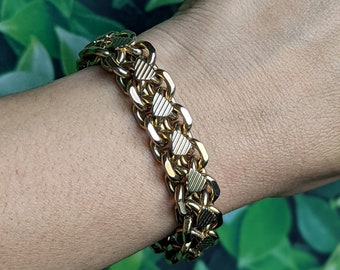 May include: A gold chain bracelet with a heart-shaped design. The bracelet is made of interlocking links and has a polished finish.
