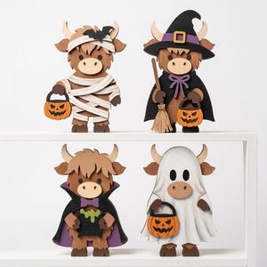 May include: Four wooden highland cow figurines dressed for Halloween. One is a mummy with a pumpkin bucket, one is a witch with a broom and pumpkin, one is a vampire with a green potion cauldron, and one is a ghost holding a pumpkin bucket.